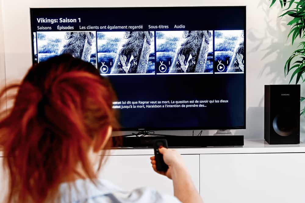 Woman holding a tv remote control In the process of selecting the viking success series proposed by Prime Video, a video-on-demand service