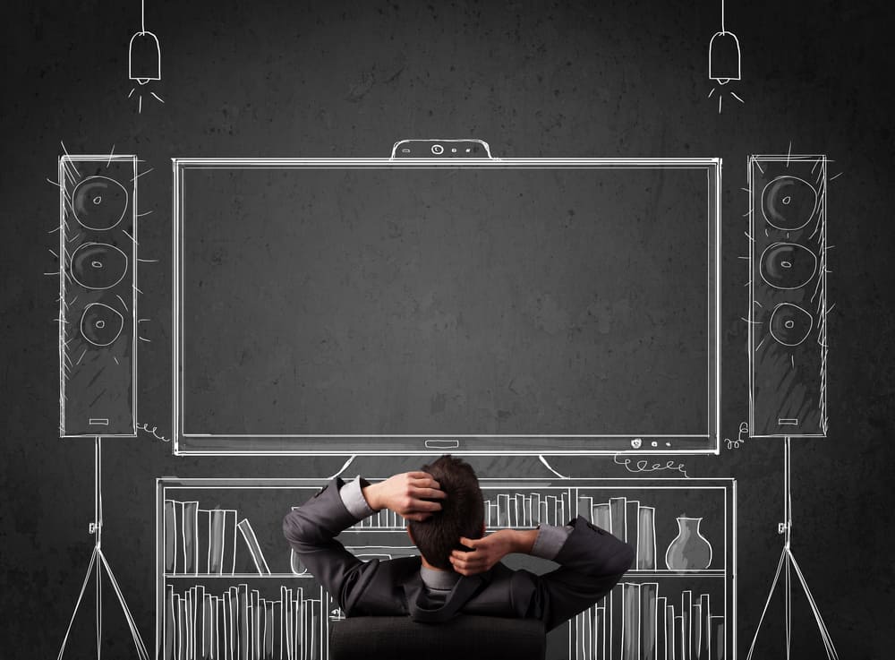 Young businessman sitting and enjoying home cinema system sketched on a chalkboard