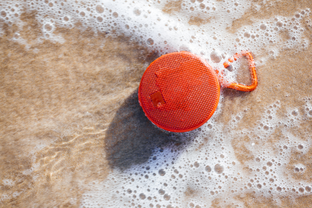 Waterproof wireless speaker on the beach wet by the waves