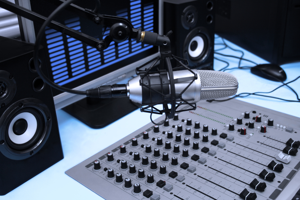 A mic in front of the control panel and screen in broadcasting studio